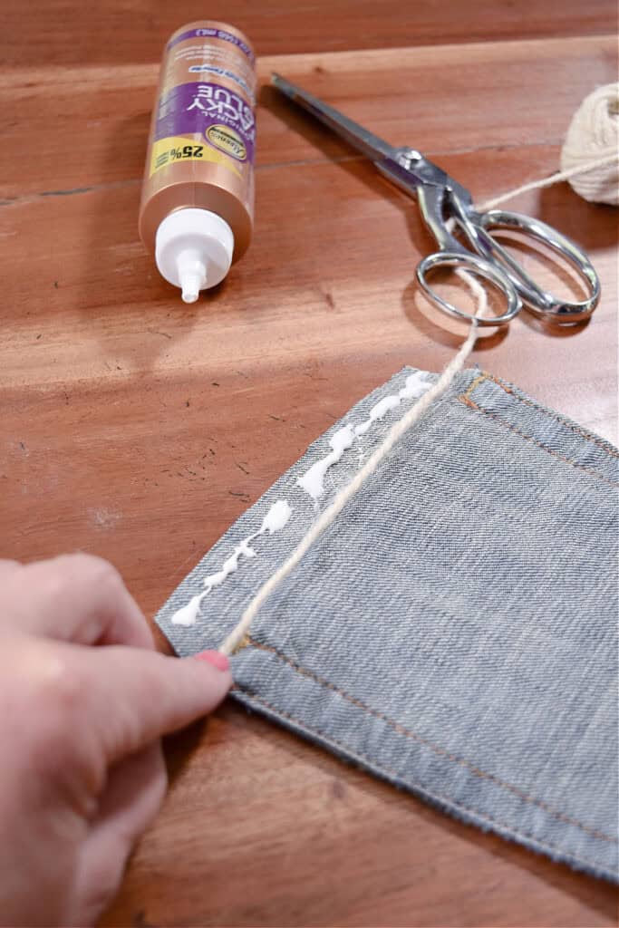 Crafting jean pocket garland with tacky glue.
