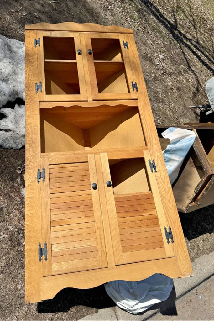 Wooden corner cupboard in curbside pile.