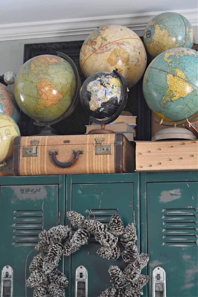 Vintage suitcase, old books and globe collection displayed on green lockers.