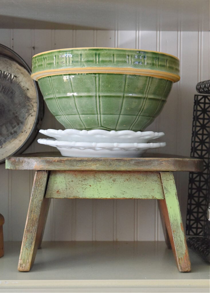 Vintage green mixing bowl on green wooden stool.