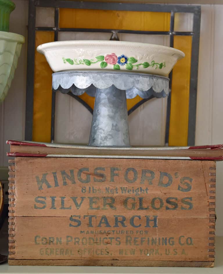 Vintage wooden box with cake plate and ovenware in kitchen cupboard.