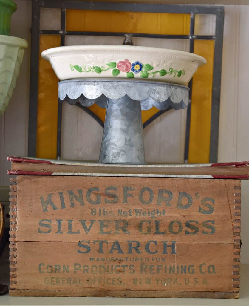 Vintage wooden box with cake plate and ovenware in kitchen cupboard.