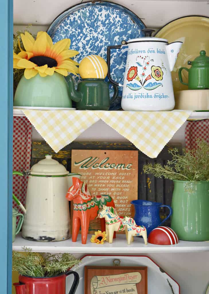 Colorful vintage enamelware display on shelves with Scandinavian accents.
