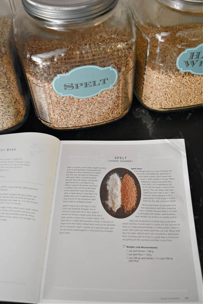 Open cookbook and spelt grain in glass jar.