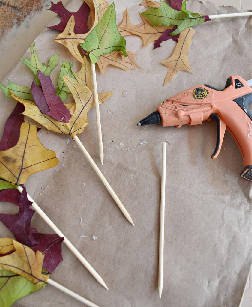 Hot gluing leaves to wood skewers.