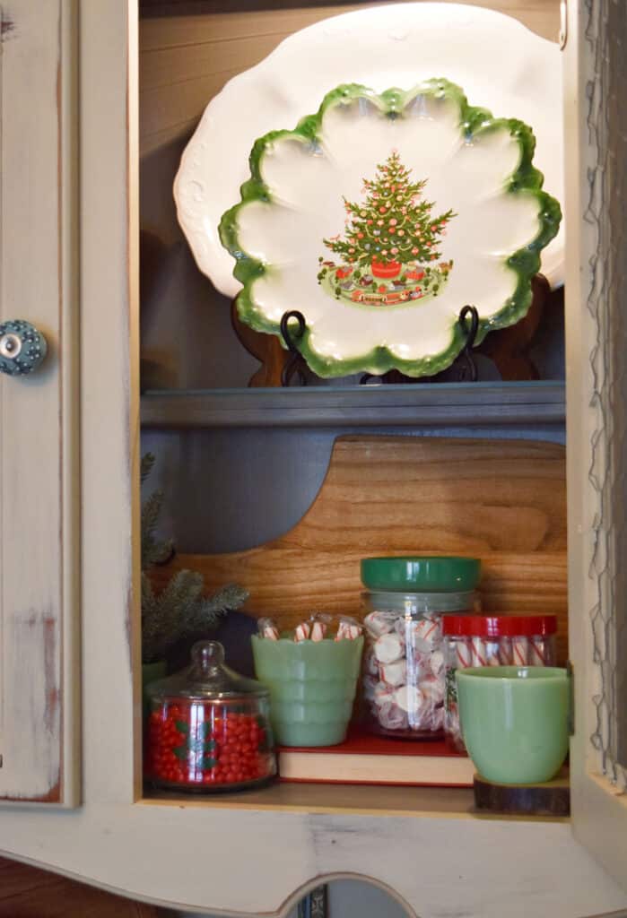 Christmas tree plate and candy decorations in hutch.