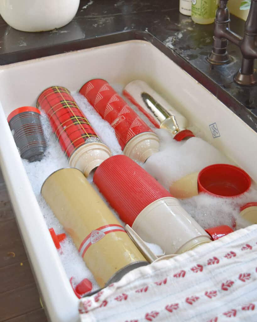 Vintage thermoses being washed in sink.
