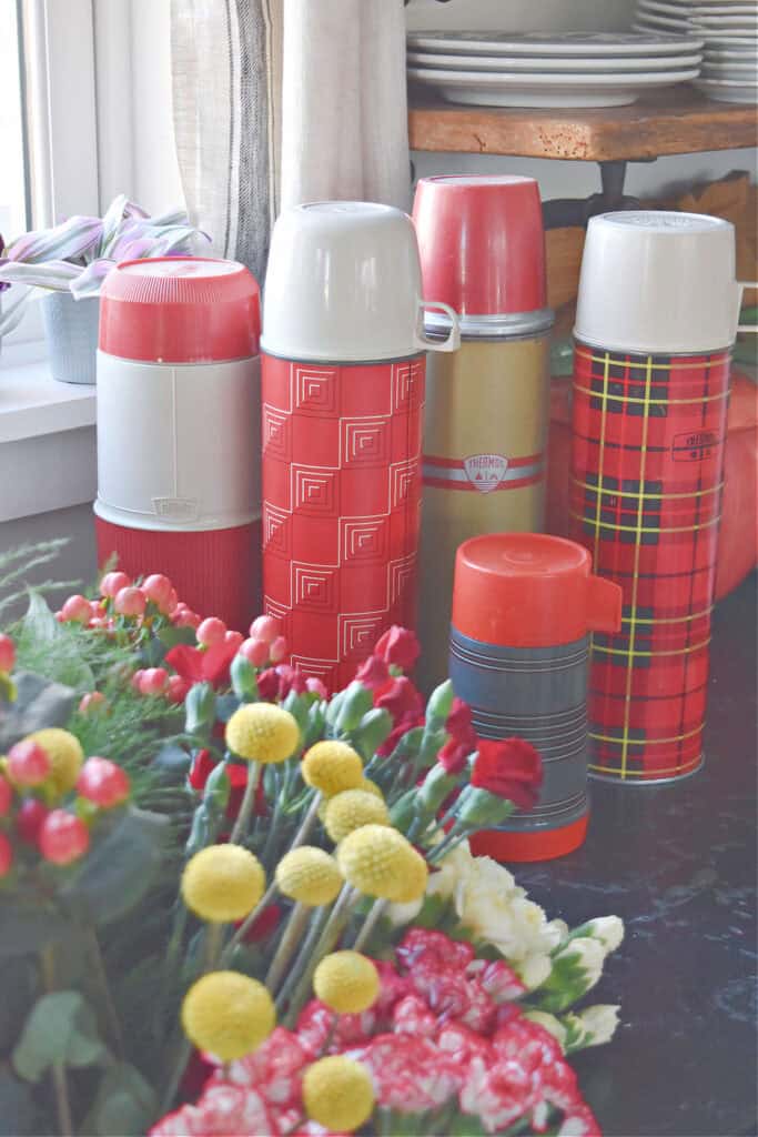 Vintage red thermoses and fresh flowers.
