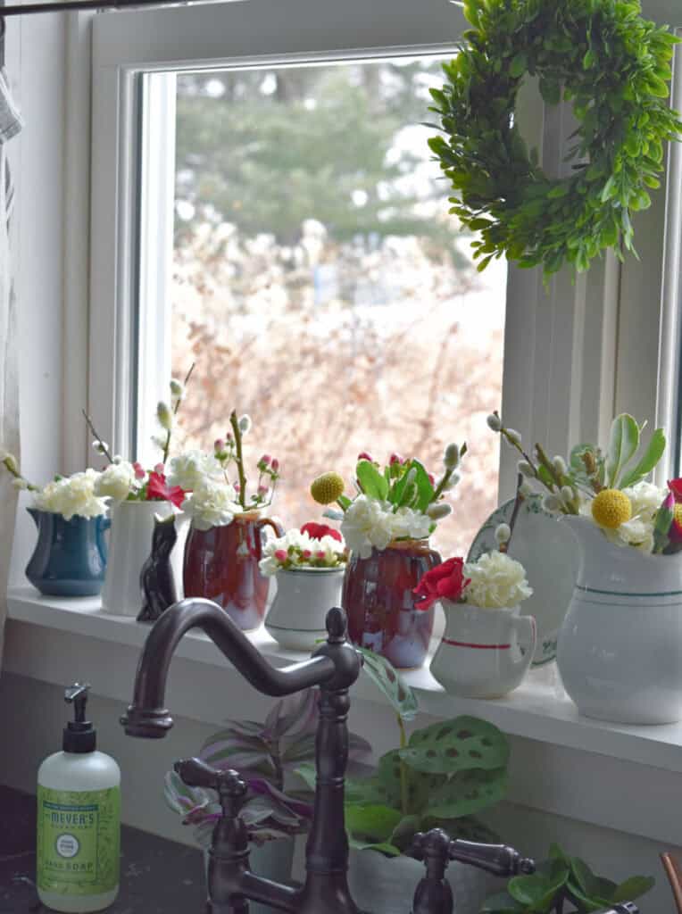 Windowsill display of vintage restaurant ware pitchers.