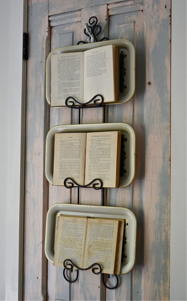 Old books layered over trays decorating a plate rack.
