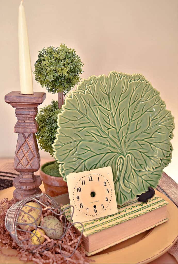 Green leaf plate and wooden candle on platter centerpiece.