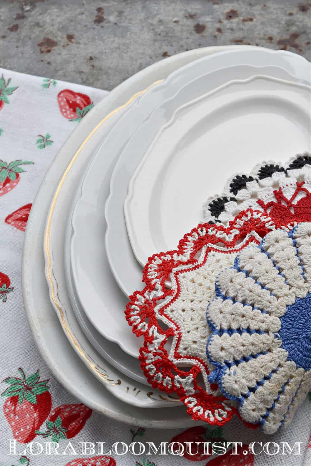 Stack of white ironstone platters and vintage crochet hot pads.