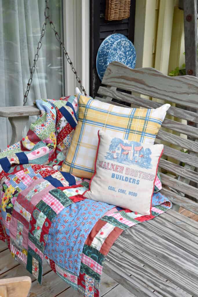 Vintage patchwork quilt and pillows as summer porch decor.