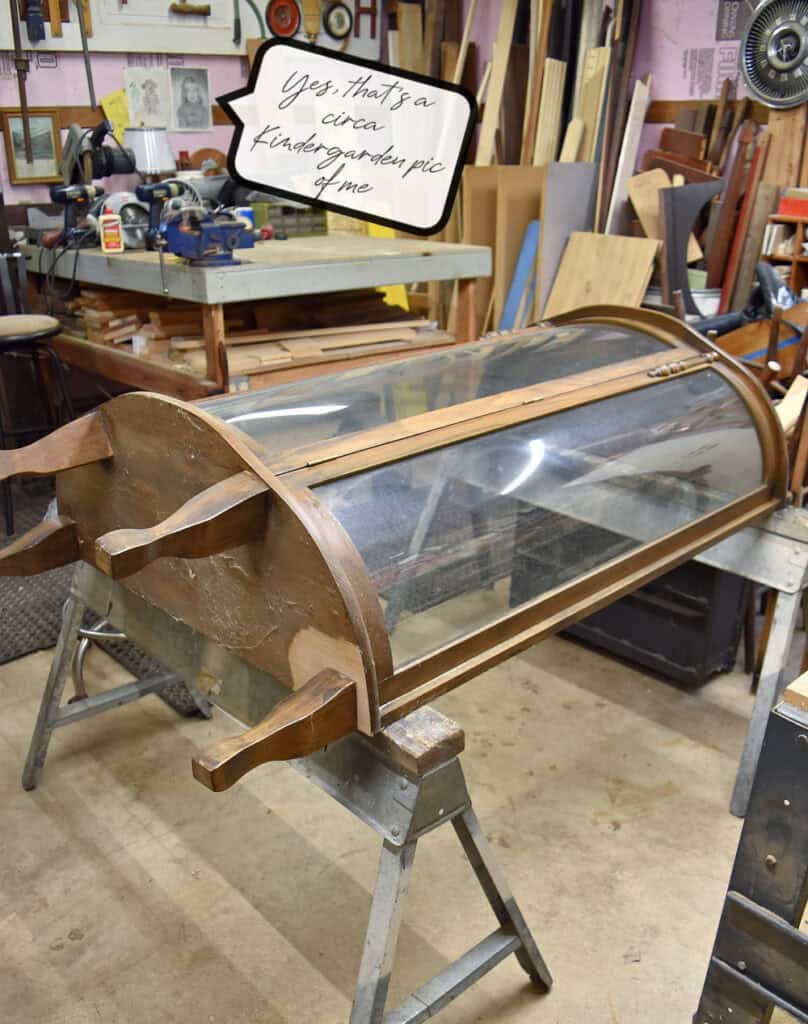 Vintage curved glass front cabinet laying on sawhorses.