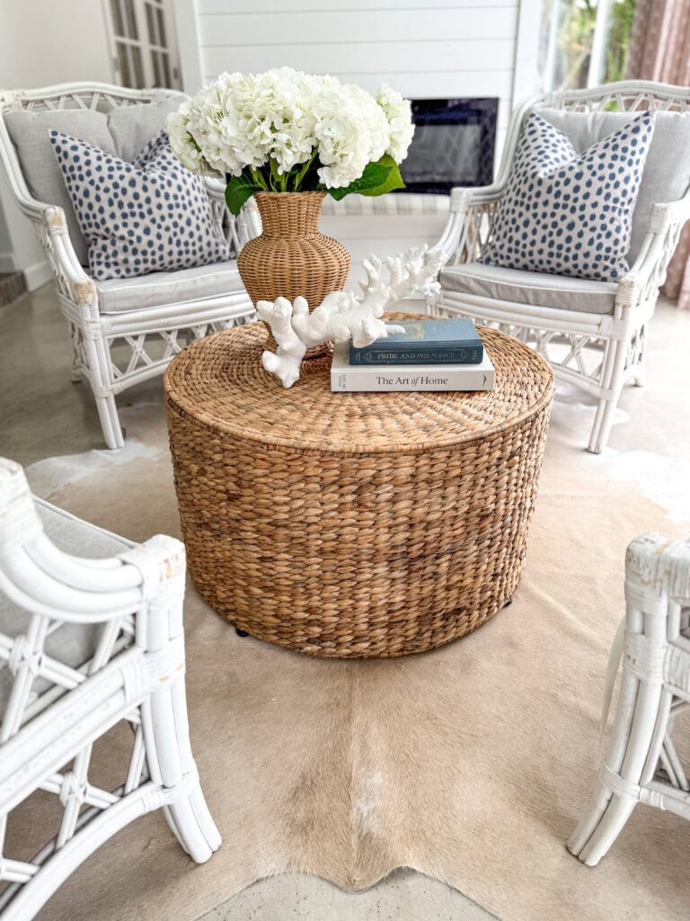 Round rattan coffee table with white chairs around