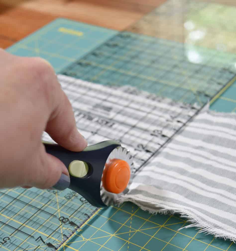 Cutting fabric with rotary pinking shears.