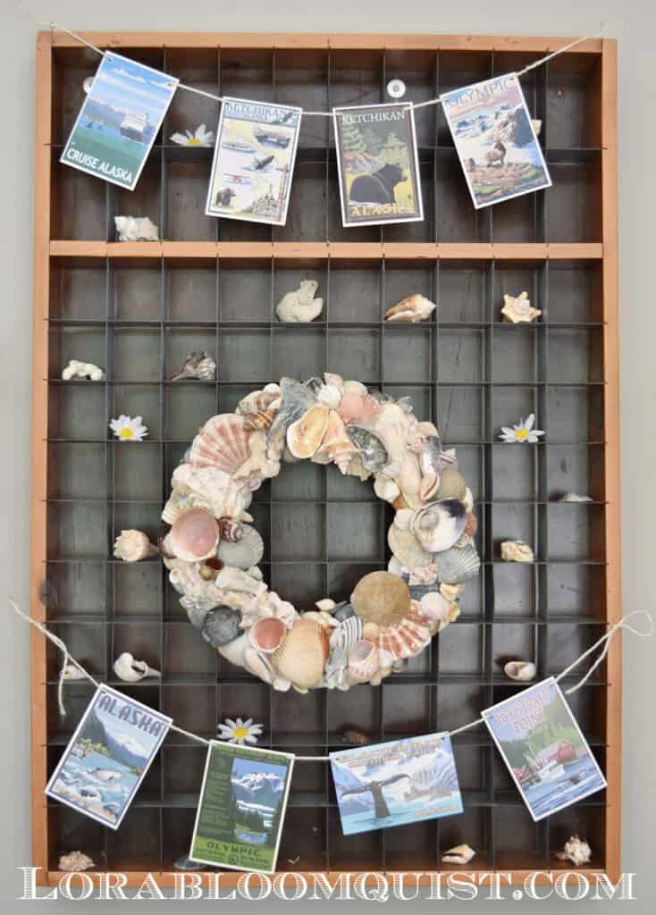 DIY seashell wreath displayed with travel postcard banner.