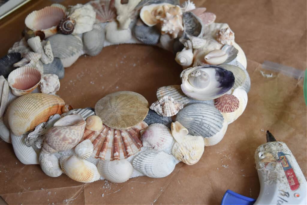 Gluing seashells to styrofoam wreath.