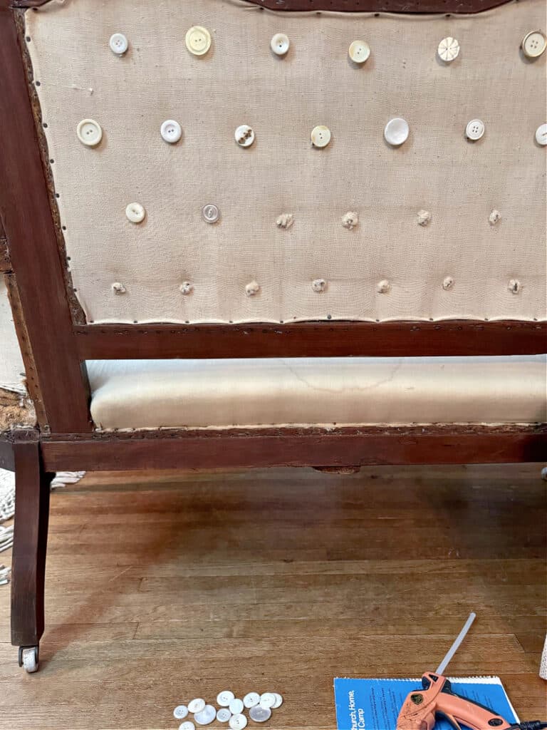 Glueing old buttons on back of antique settee.