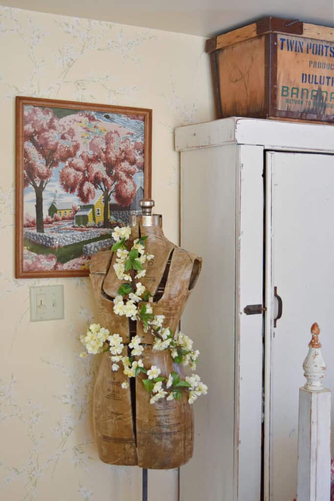 Vintage dress form with floral garland and barkcloth framed art.