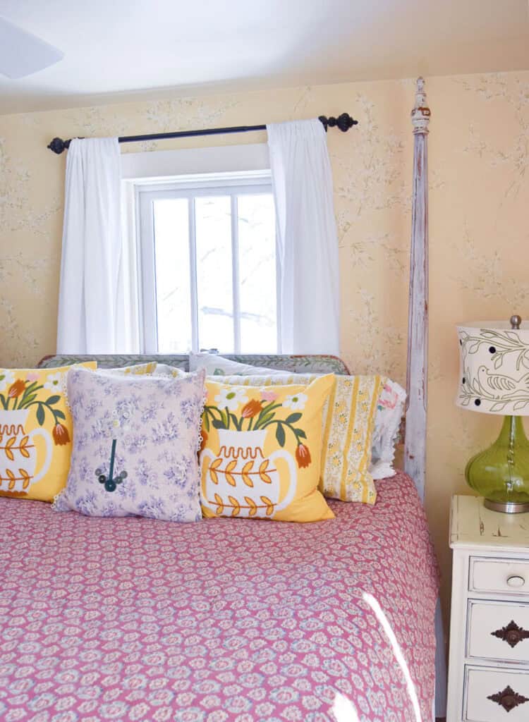 Vintage rose colored quilt on bed with yellow flowered pillows.