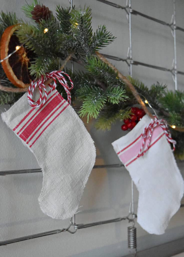Handcrafted scrap fabric mini Christmas stockings hanging on evergreen garland.