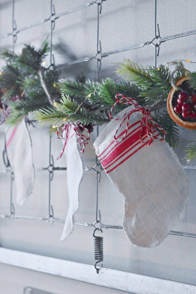 Handcrafted scrap fabric mini Christmas stocking hanging on evergreen garland.