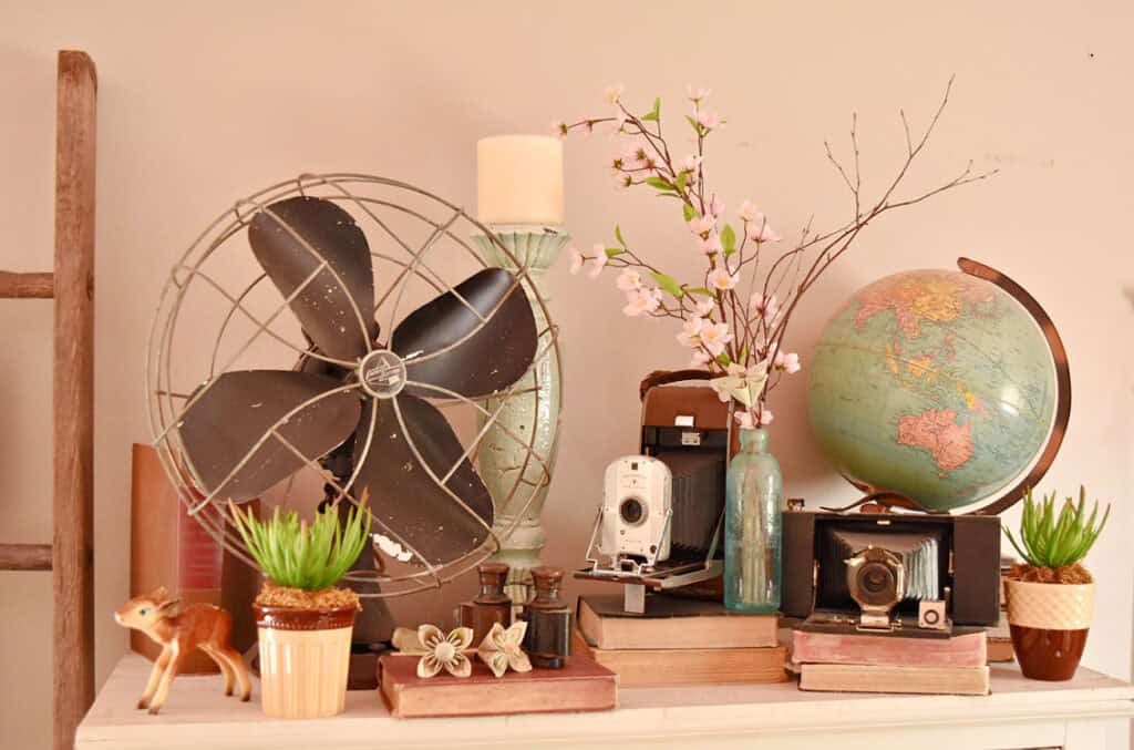 Faux apple blossoms and sticks in vase as Spring decor with vintage accessories.