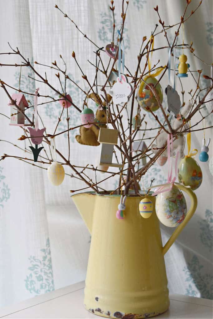 Easter tree with forced branches in yellow enamelware pitcher.