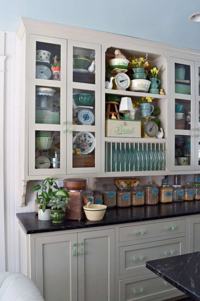 Farmhouse kitchen cabinets with vintage green collections and wheat berries in glass jars.