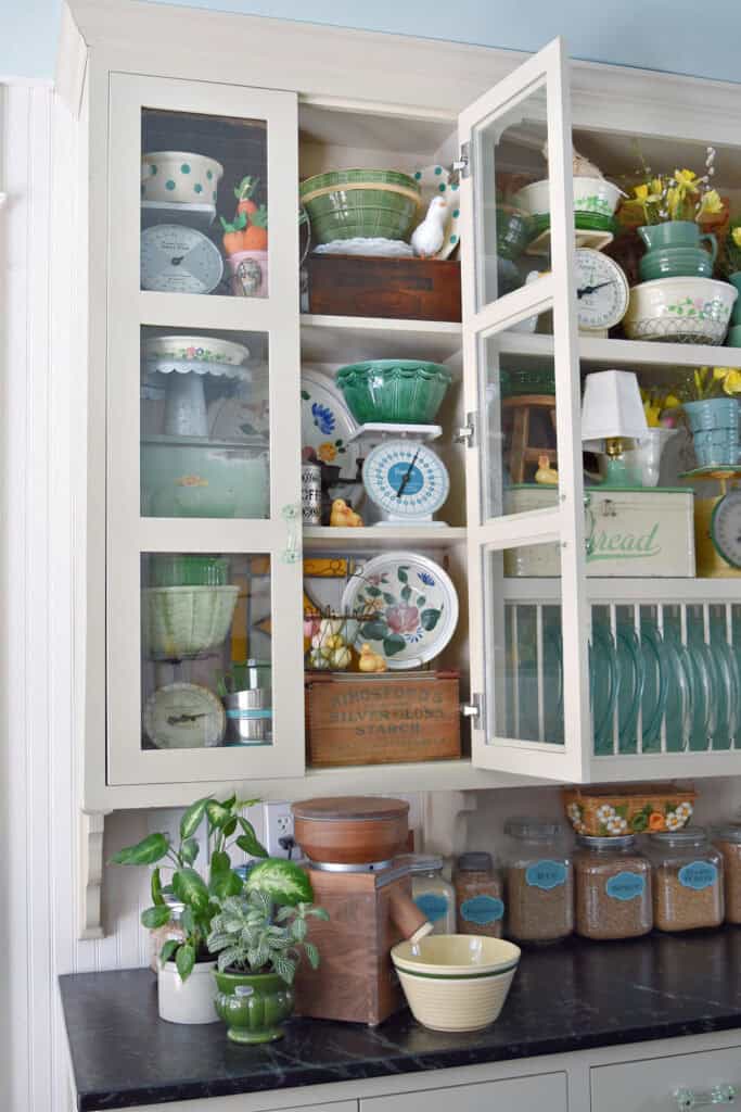 Farmhouse kitchen cabinets with vintage green collections and wheat berries in glass jars.
