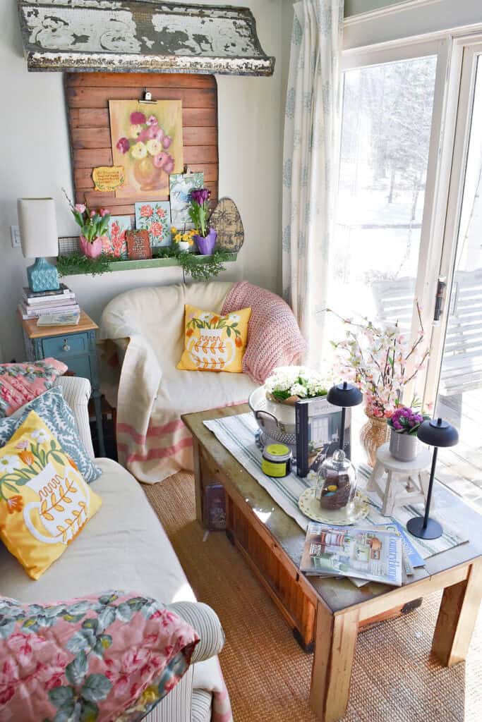 Cozy kitchen sitting area decorated for Spring with vintage art and pastel pillows.