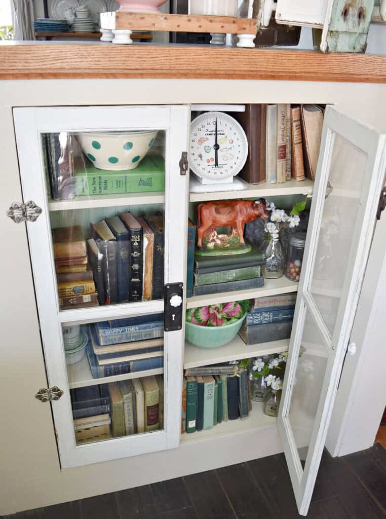 Glass front cabinet with old books and vintage kitchen finds.