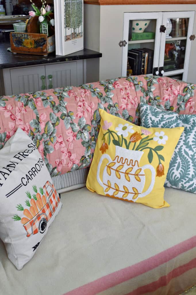 Spring pillows on loveseat with floral quilt.