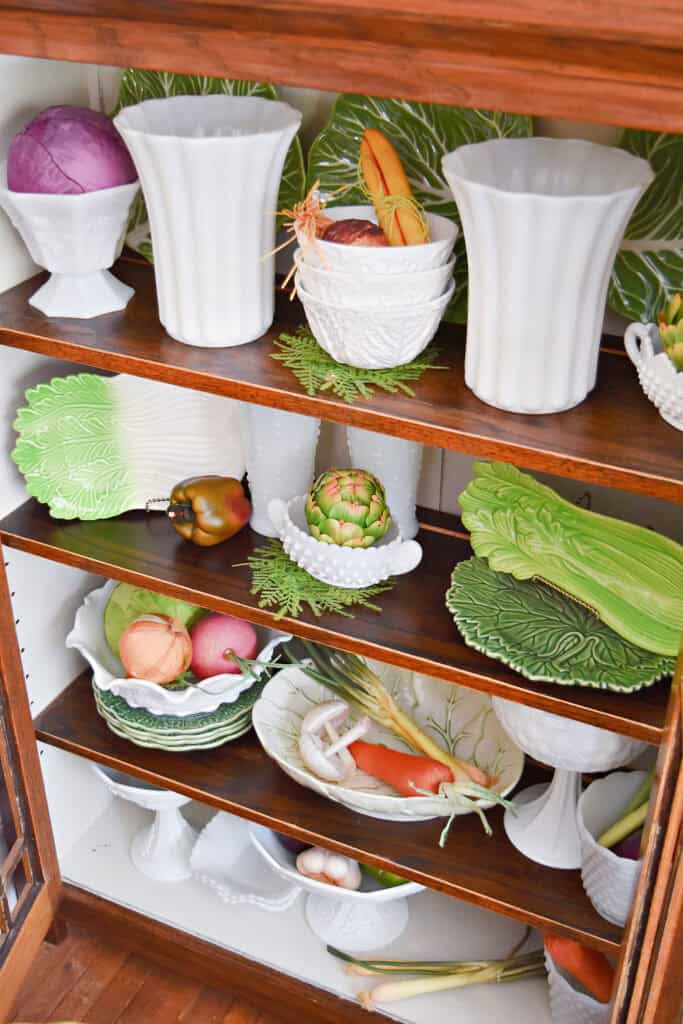 Vintage and new cabbage ware pieces and milk glass on shelf display.