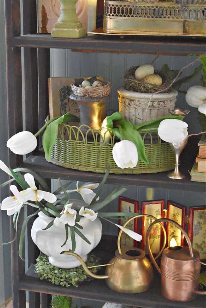 White flowers and vintage finds decorate a bookshelf for early Spring.