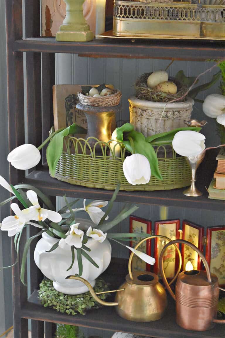 White flowers and vintage finds decorate a bookshelf for early Spring.