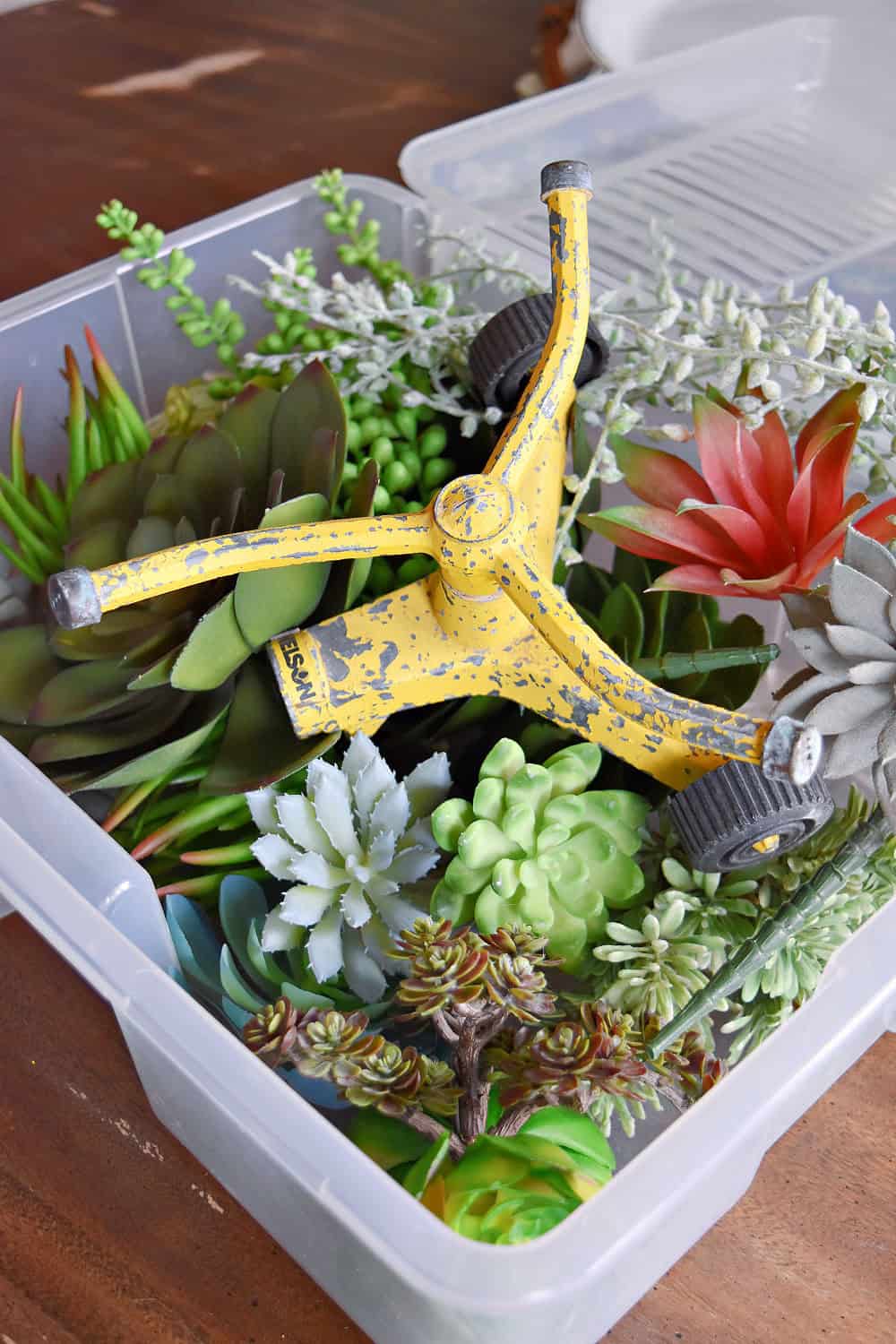 Old yellow sprinkler and faux succulents.