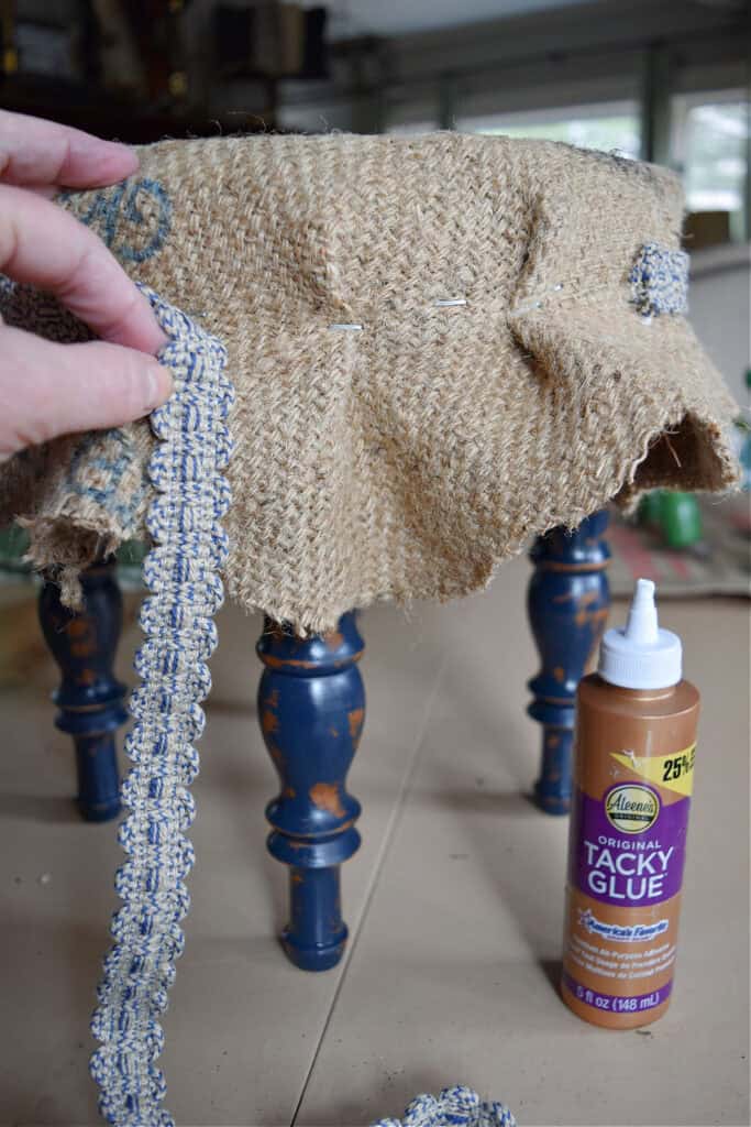 Gluing trim on footstool makeover.