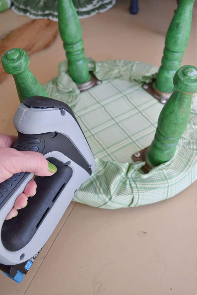 Stapling fabric onto old stool for makeover.
