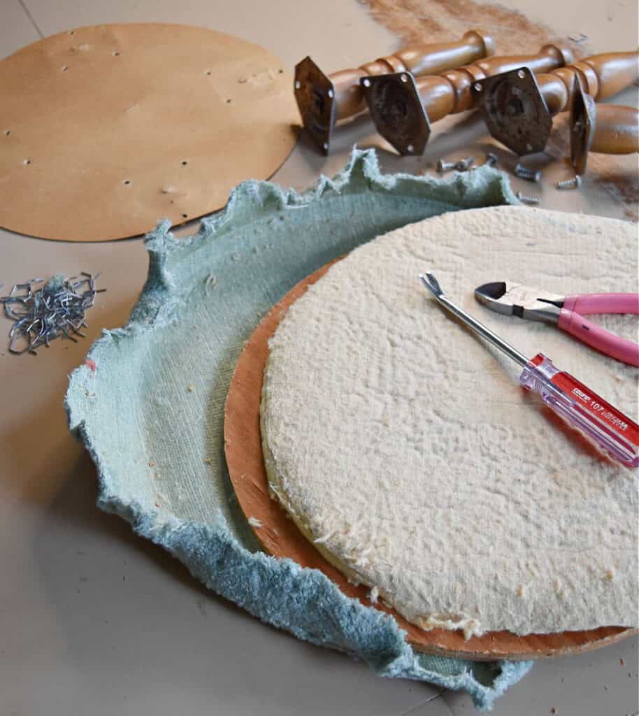 Taking fabric off of old upholstered footstools.
