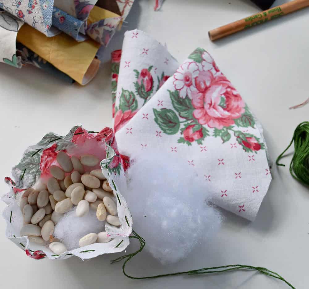 Filling fabric strawberries with filling and dried beans.