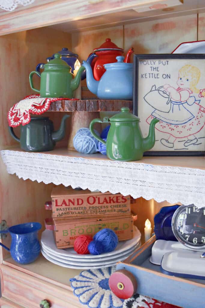 Vintage enamelware teapot collection in summer hutch display.