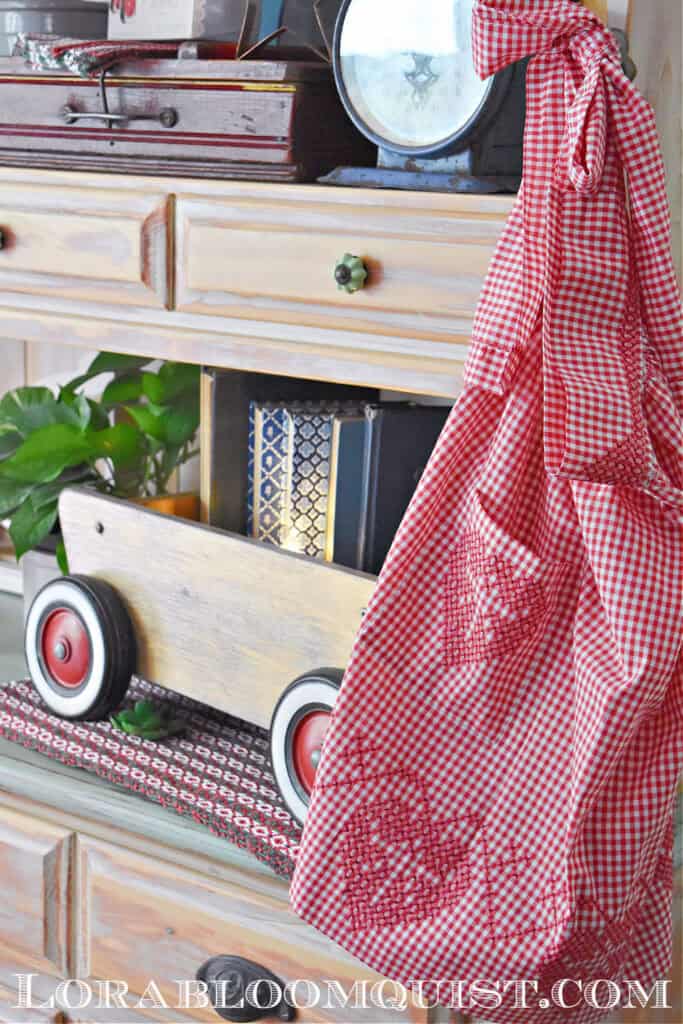 Red and white gingham vintage apron and old pull toy as display.