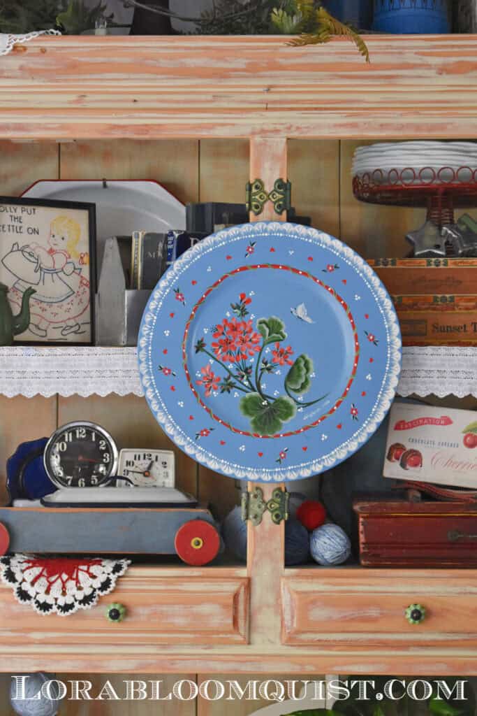 Blue hand painted wooden plate in summer hutch display.