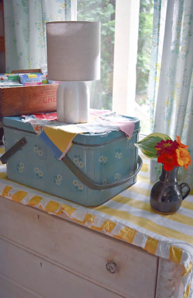 Vintage aqua metal picnic basket on yellow stripe runner.