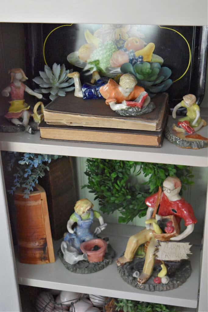 Handmade pottery people in cupboard display.