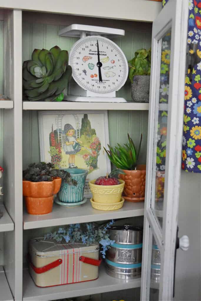 Vintage colorful planters in cupboard display.