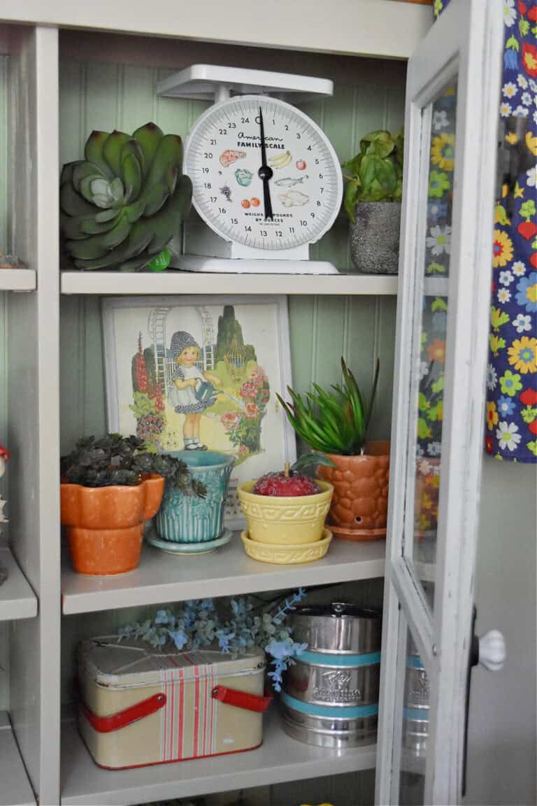 Vintage colorful planters in cupboard display.