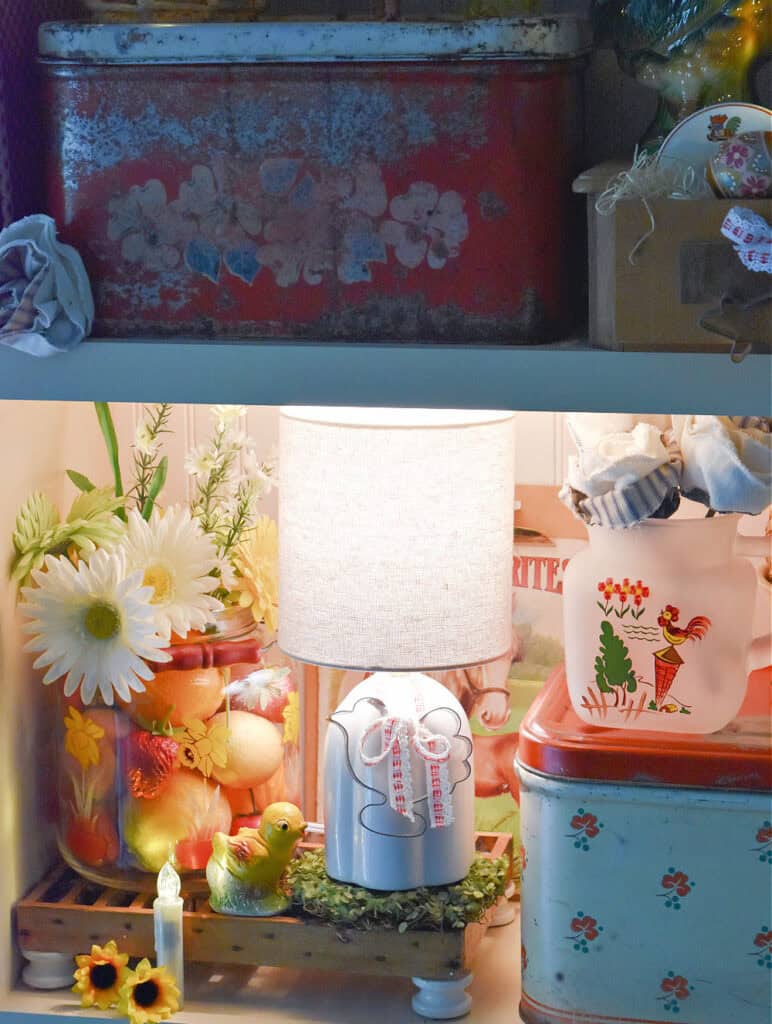 White lamp in kitchen display with fruit and flowers.